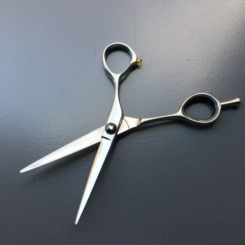 Eine geöffnete Friseurschere aus Edelstahl auf dunklem Grund